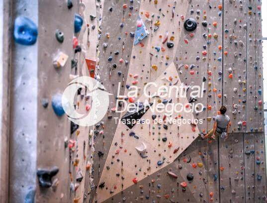 Wide angle view of Caucasian athlete in late 20s practicing on vertical wall in modern indoor rock climbing gym. Wide angle view of Caucasian athlete in late 20s practicing on vertical wall in modern indoor rock climbing gym.